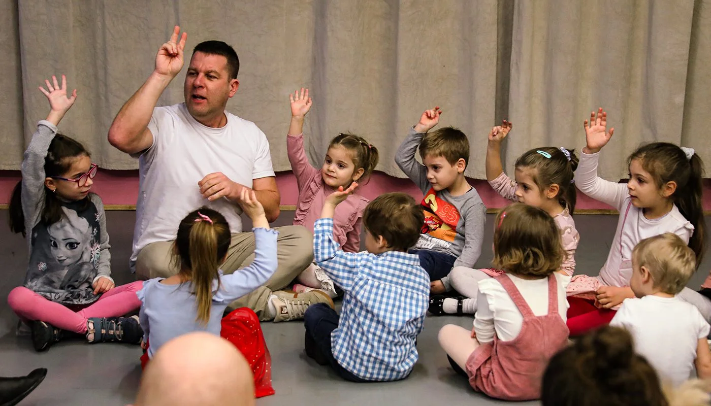 Ricsi bácsi játékos foglalkozást tart egy körben ülő gyerekcsoportnak